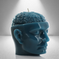 A teal soy candle shaped like a human head with an exposed brain design, featuring a wick on top. Bold and detailed.