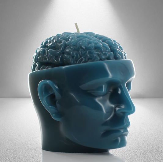 A teal soy candle shaped like a human head with an exposed brain design, featuring a wick on top. Bold and detailed.