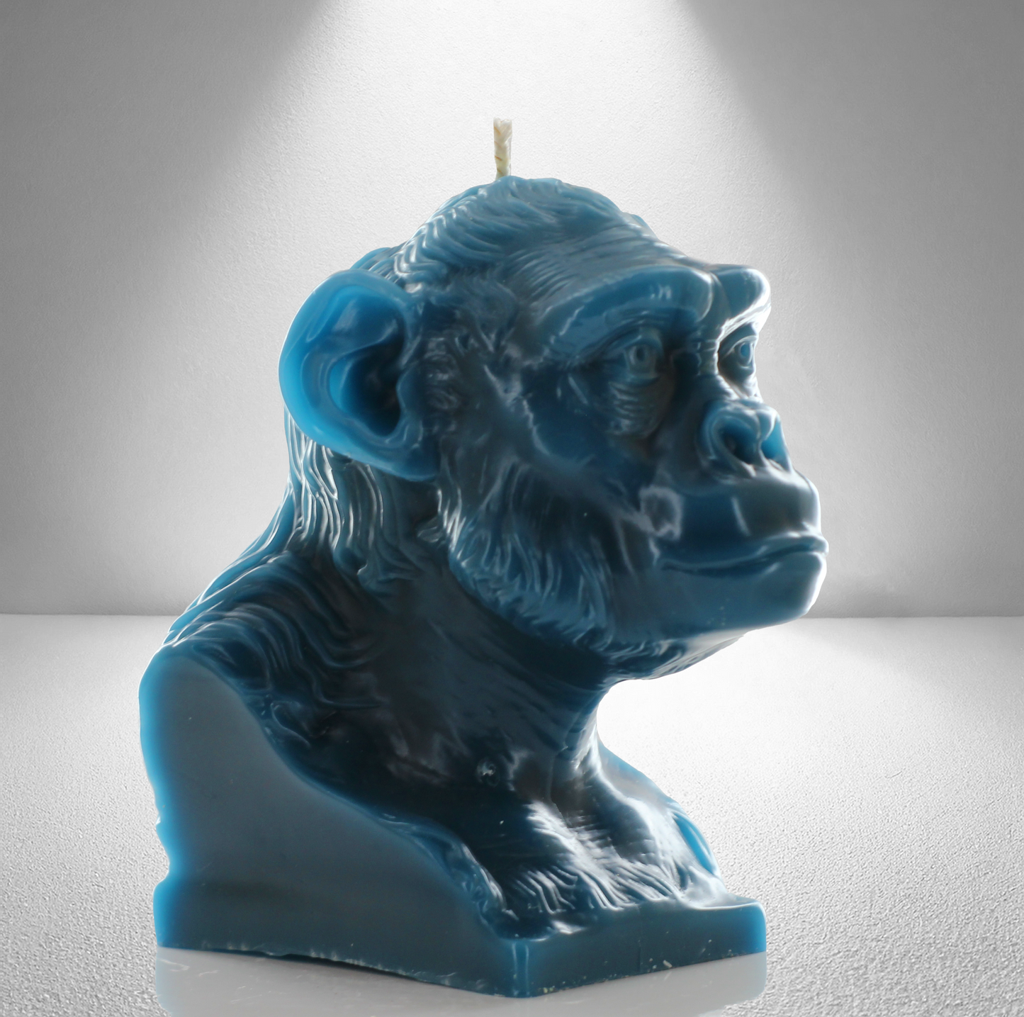 Teal unscented candle shaped like a chimpanzee, featuring detailed facial and fur textures. Bold and expressive design.