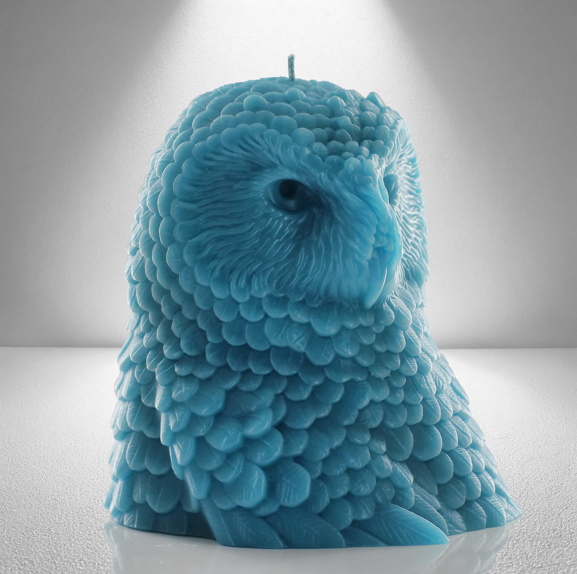 Aquamarine owl shaped candle with detailed feather design, set against a gray background