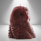 Dark red owl shaped candle with detailed feather design, set against a gray background