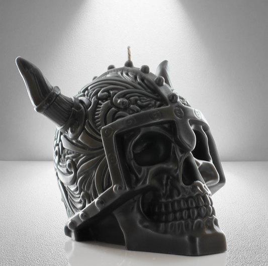 Part side view of a dark grey unscented candle shaped like a Viking skull with intricate details and a horned helmet design. Bold and striking.