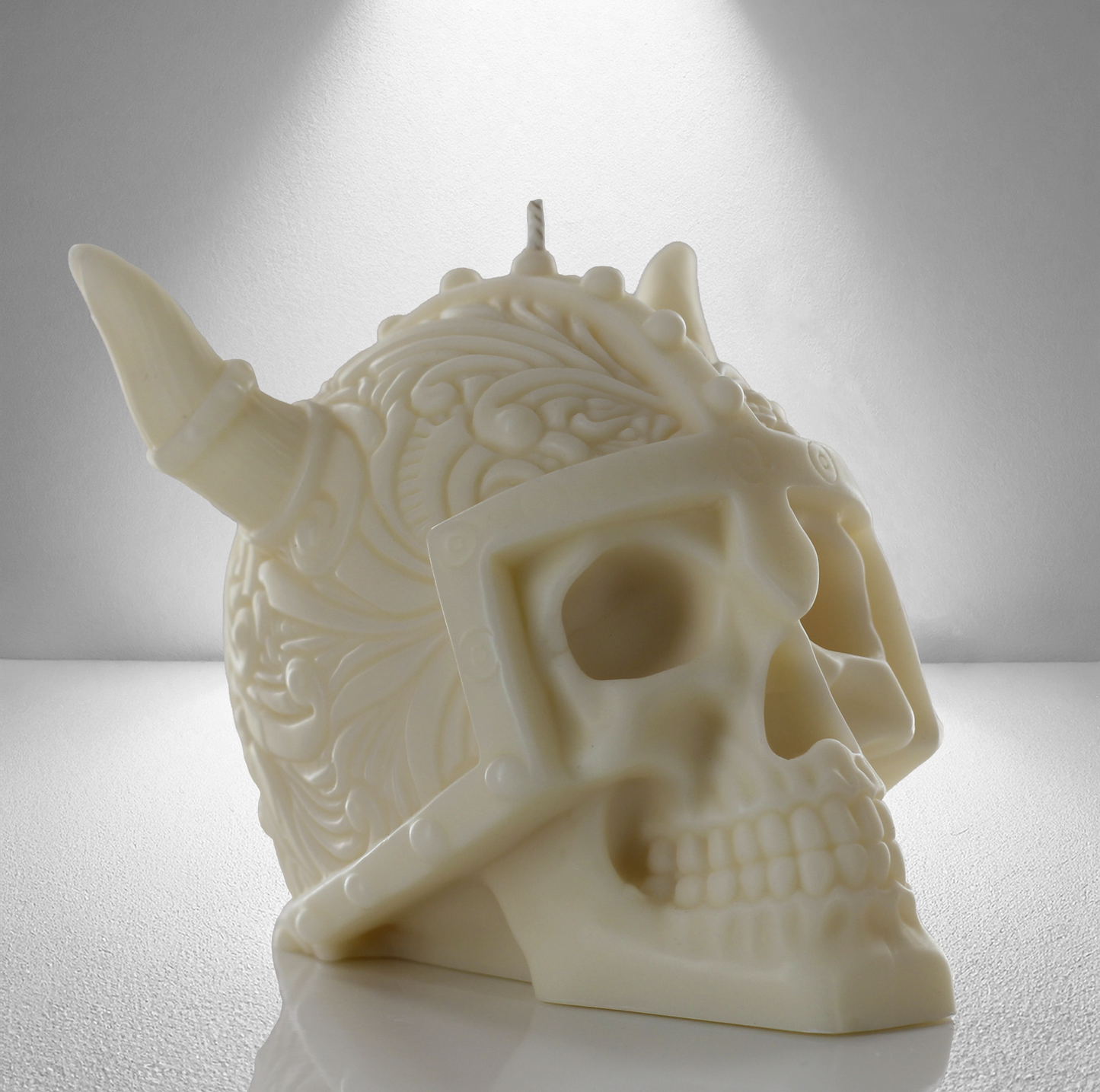 Part side view of a soy coloured unscented candle shaped like a Viking skull with intricate details and a horned helmet design. Bold and striking.