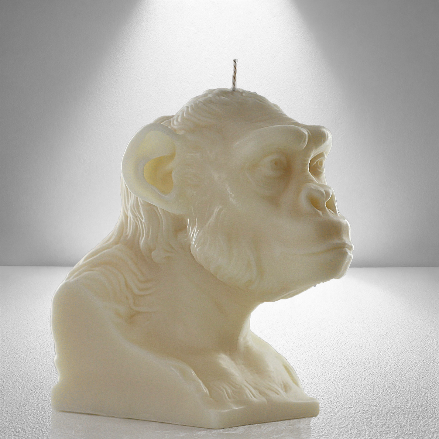 45 degree side view of a soy unscented candle shaped like a chimpanzee, featuring detailed facial and fur textures. Bold and expressive design.