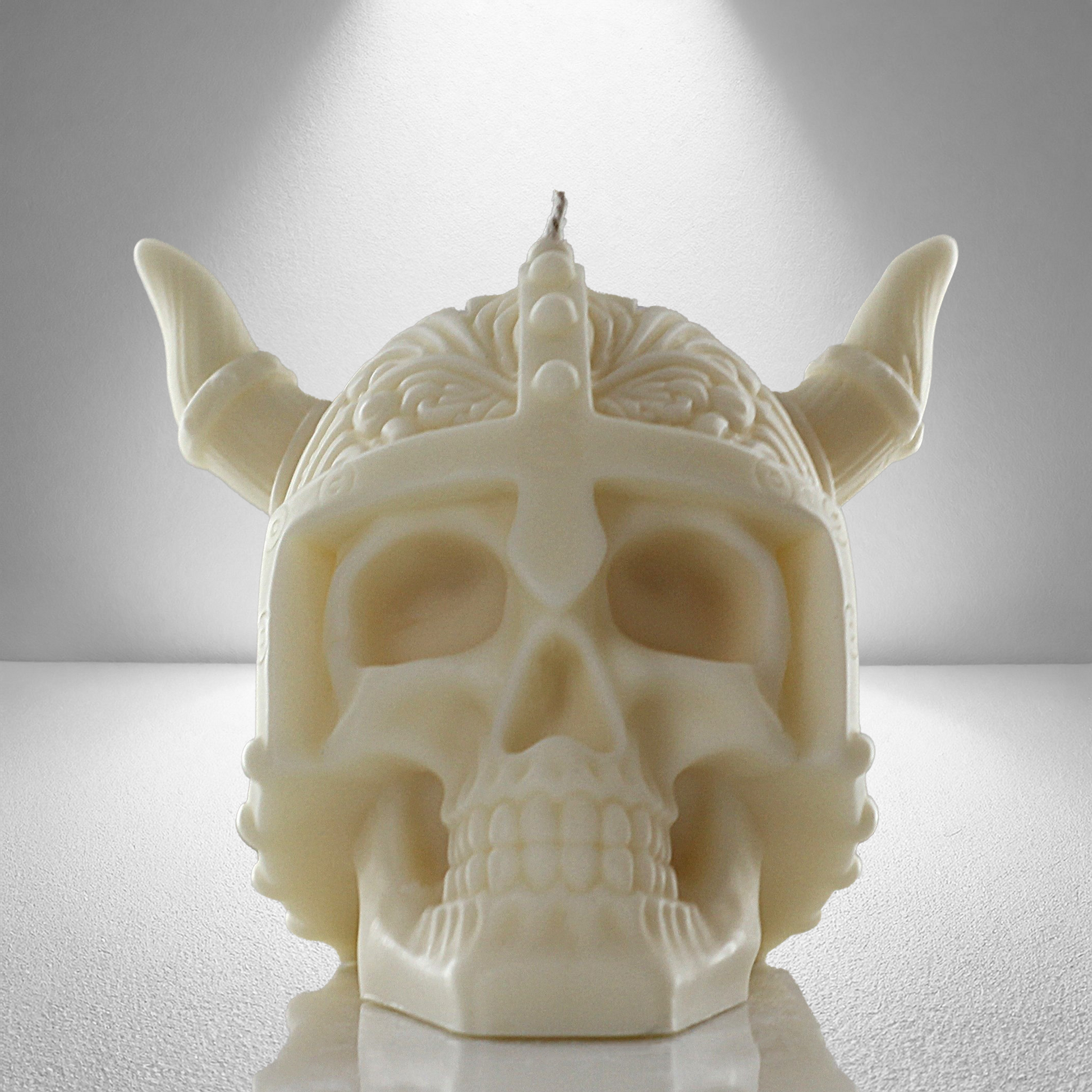 Front view of a soy coloured unscented candle shaped like a Viking skull with intricate details and a horned helmet design. Bold and striking.