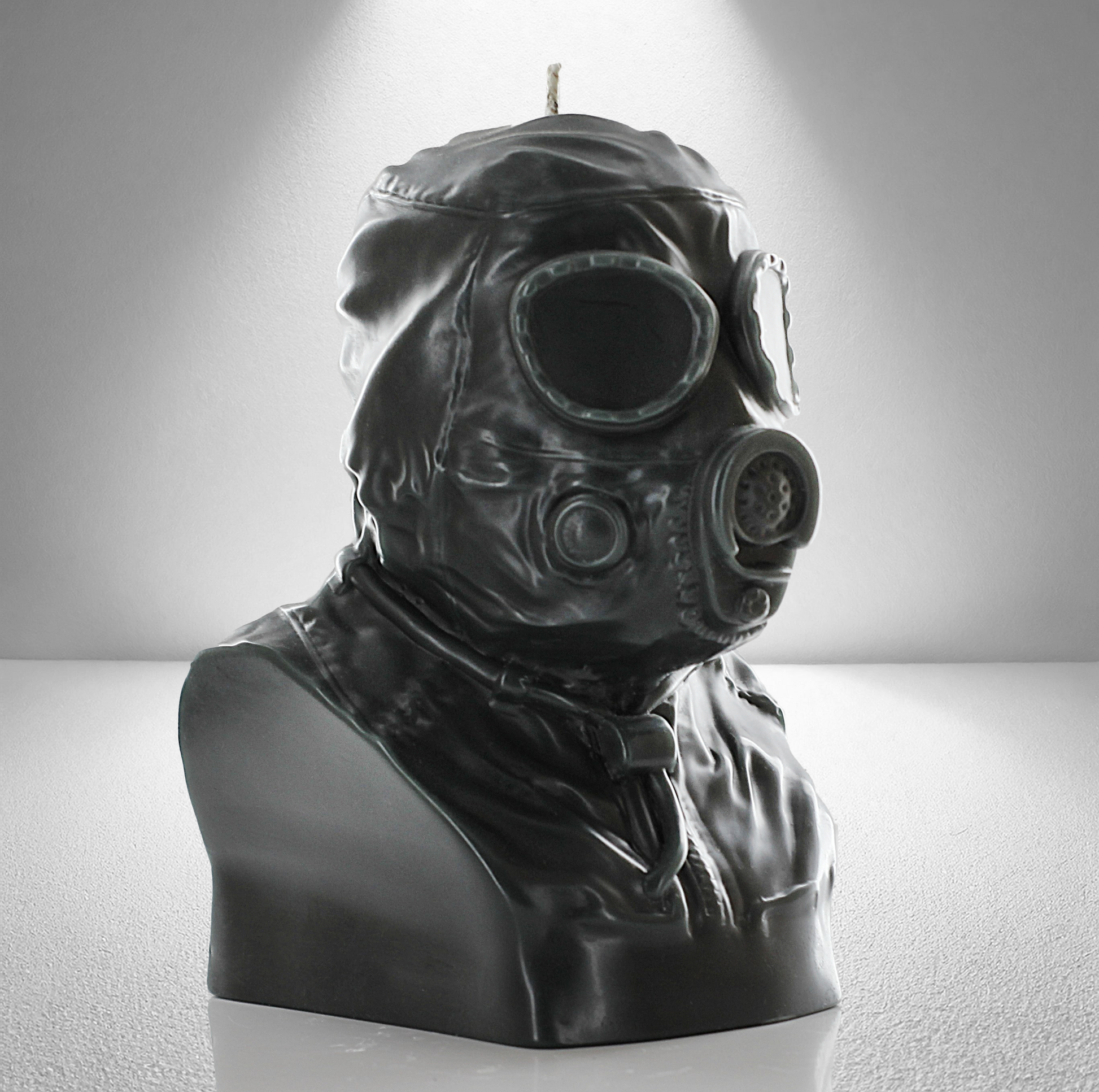 A dark grey military trooper bust candle with an intricate gas mask head design, displayed with a light grey backdrop under a spotlight.